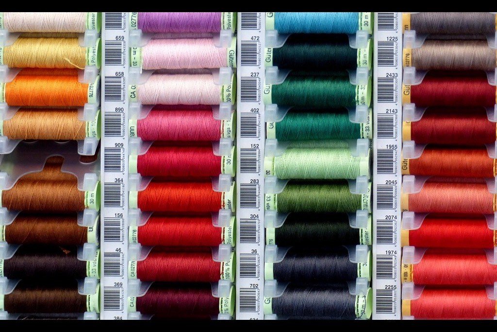 Bobines de fil de couleur alignées en atelier.